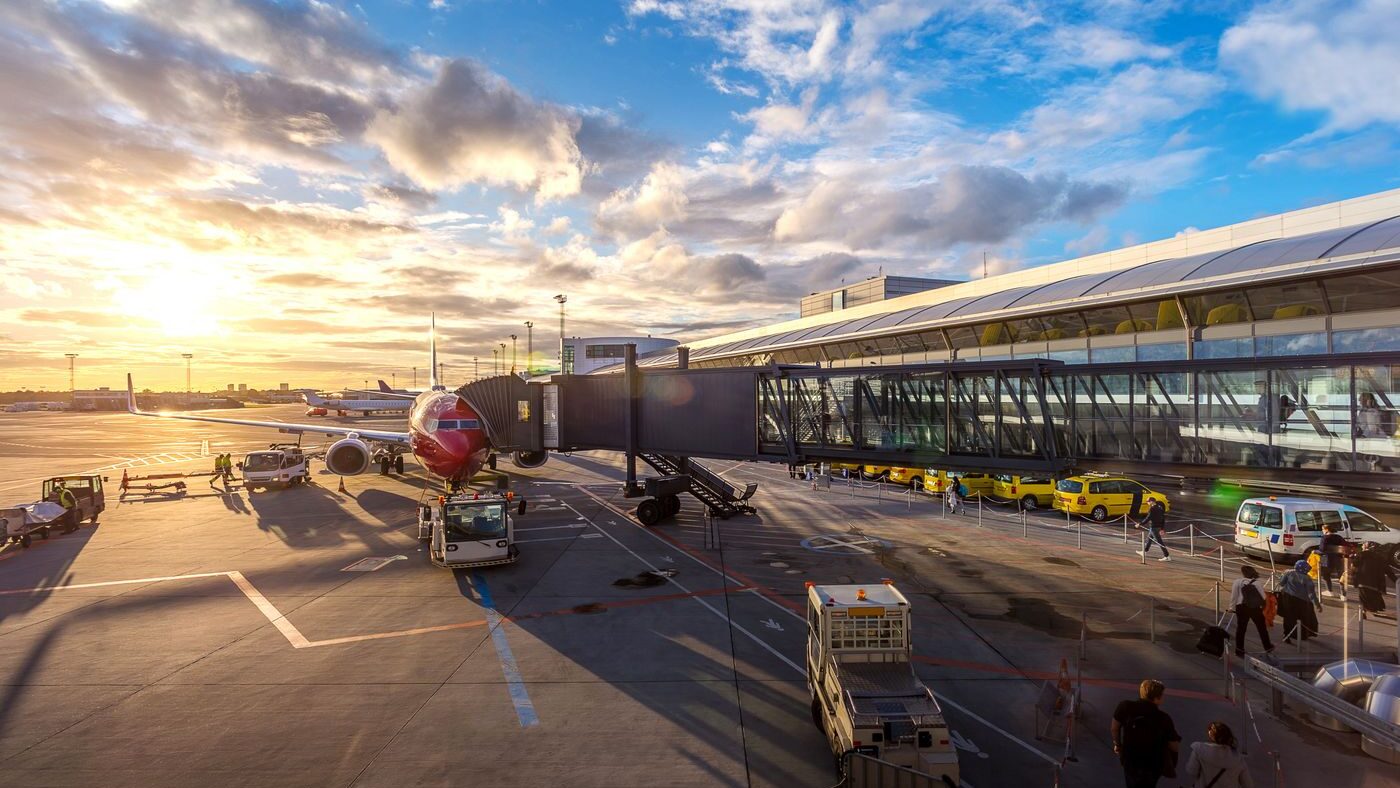 Commercial aircraft parked at an airport gate with jet bridge and terminal