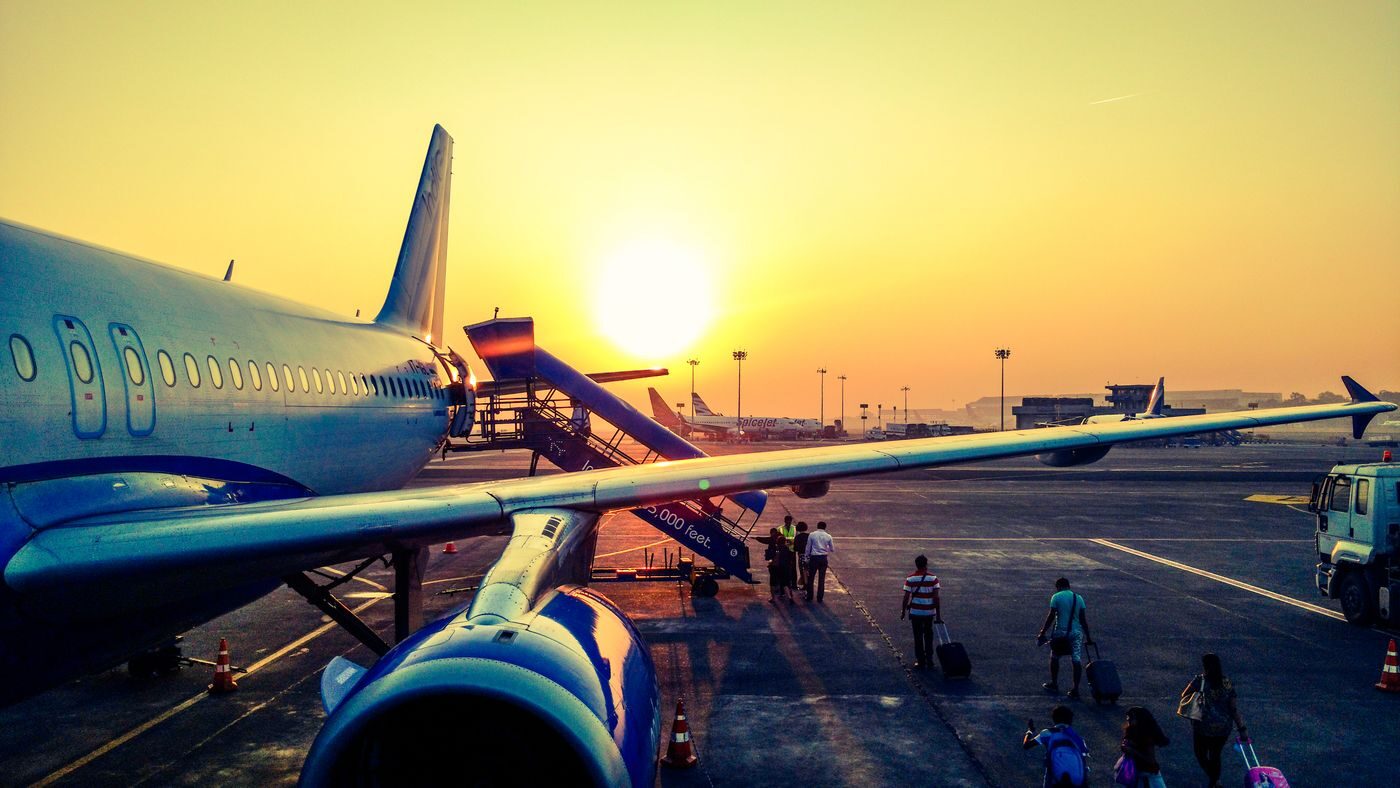 Passengers with rolling suitcases boarding an aircraft on the tarmac