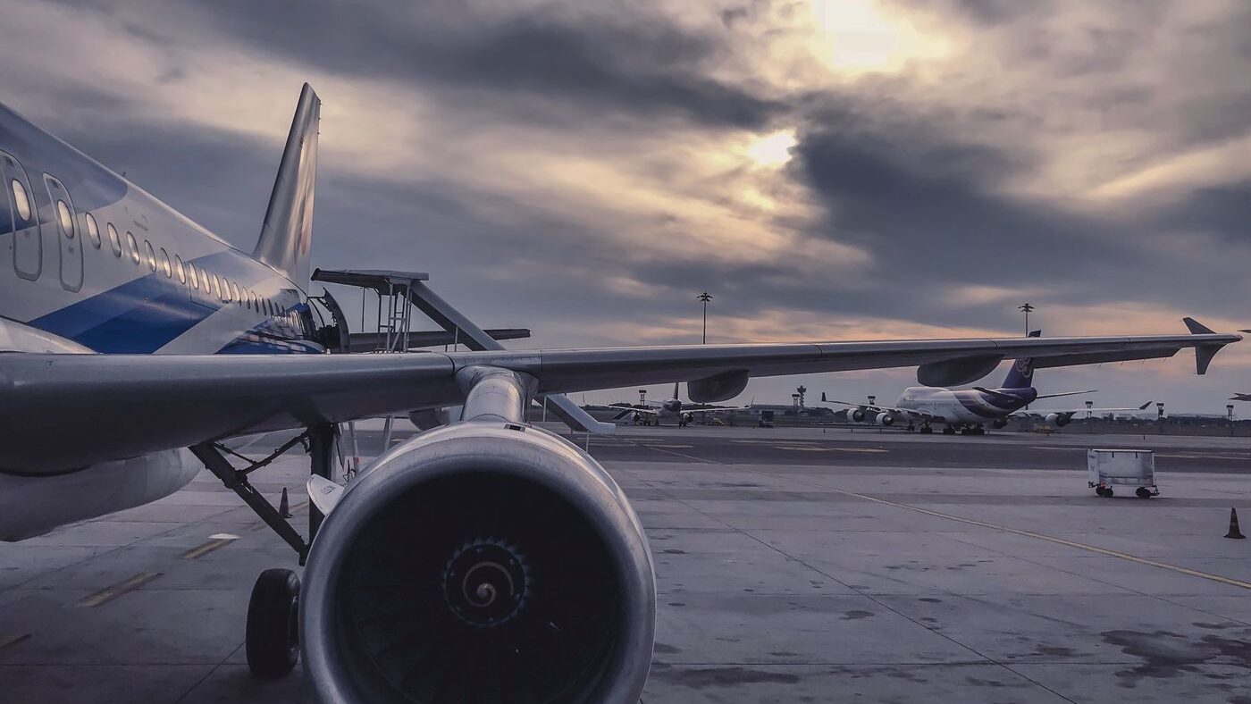 Close-up of a commercial jet engine and wing on the airport tarmac
