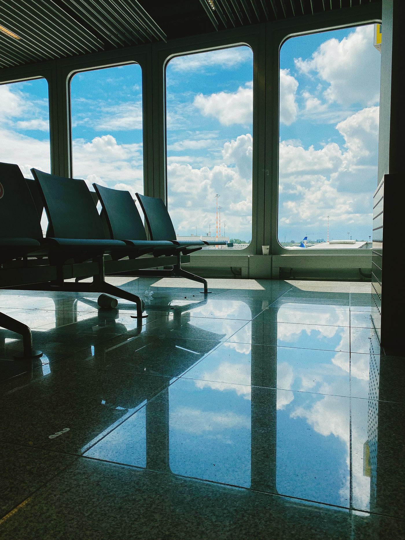 Empty airport gate seats beside windows looking onto the tarmac