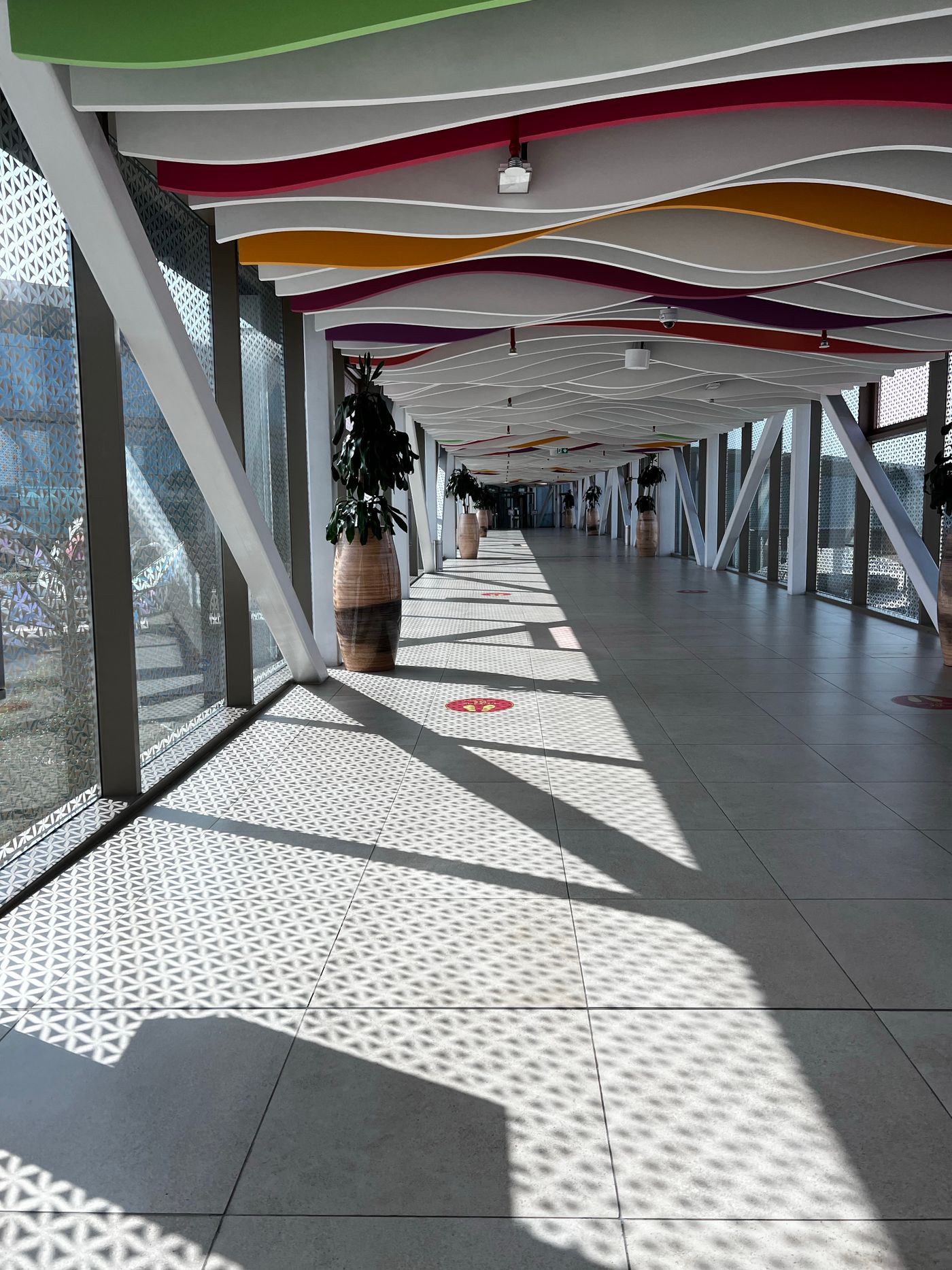 Empty airport corridor with patterned windows and a colourful ceiling