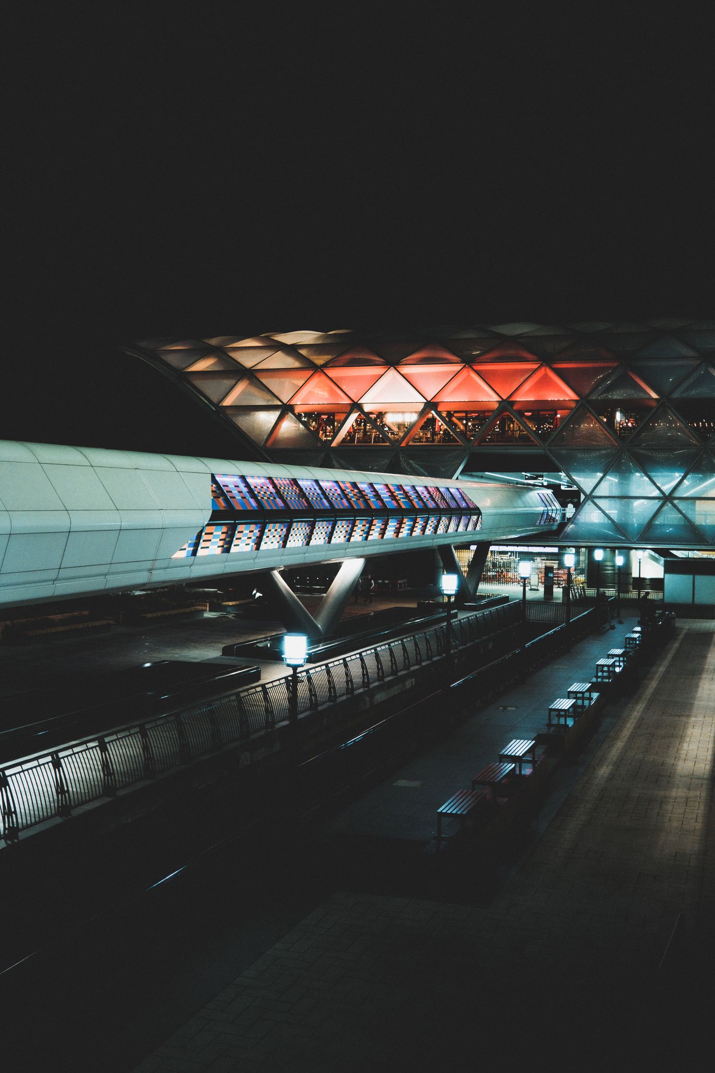Outdoor benches beside an illuminated airport terminal at night